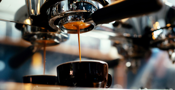 Coffee mug being filled with espresso from a machine.