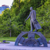 A statue of Nikola Tesla in a park near Niagara Falls. It depicts him standing on a gear while pulling a lever.