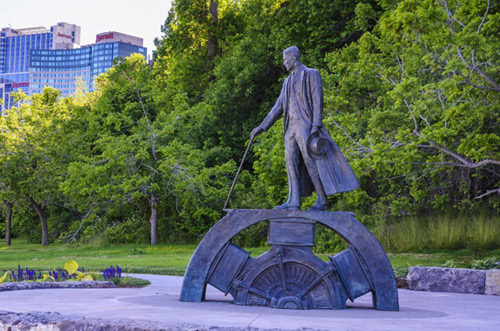 A statue of Nikola Tesla in a park near Niagara Falls. It depicts him standing on a gear while pulling a lever.