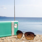 A radio and a pair of sunglasses on the beach.