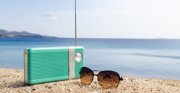 A radio and a pair of sunglasses on the beach.