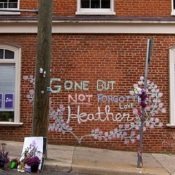 A memorial on a brick wall next to a street in Charlottesville. Graffiti is written on it, saying "Gone But Not Forgotten Heather".