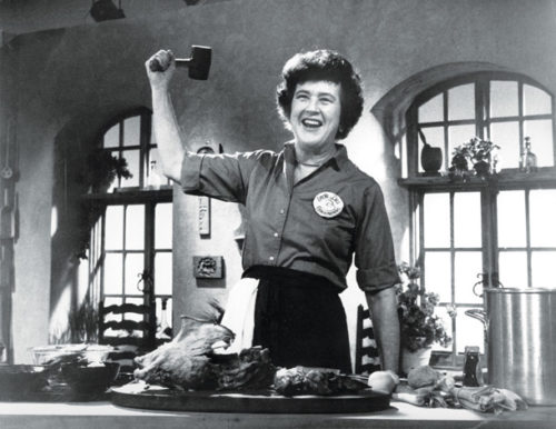 Julia Child weilding a meat mallet on her studio set.