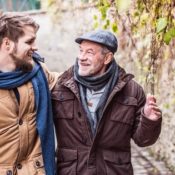A grandfather walks with his adult grandson down a street.