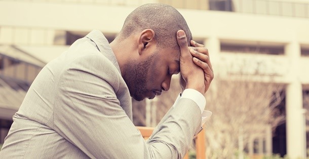 Depressed man with his head in his hands.