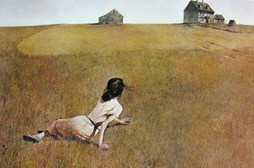 Woman in a dry field looks back at a farmhouse on the horizon.