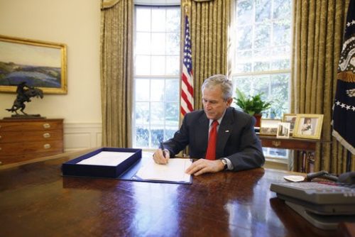U.S. President George W. Bush signing the Emergency Economic Stabilization Act of 2008 in the Oval Office.