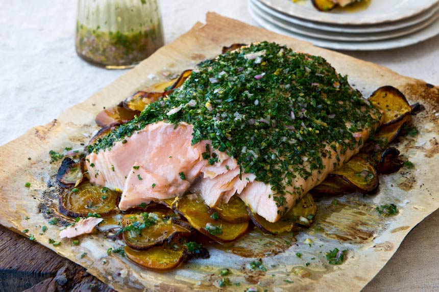 Roasted salmon covered with herbs on a wooden cutting board
