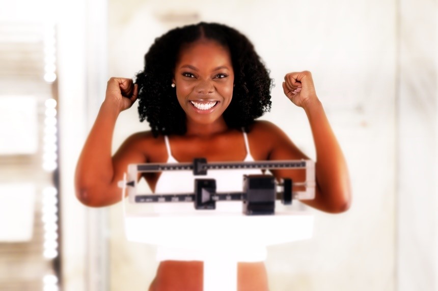 Young woman smiling on a weight scale.
