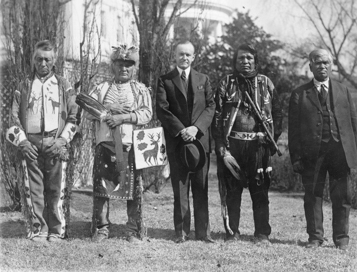 U.S. president Calvin Coolidge with Osage Indians in traditional dress.