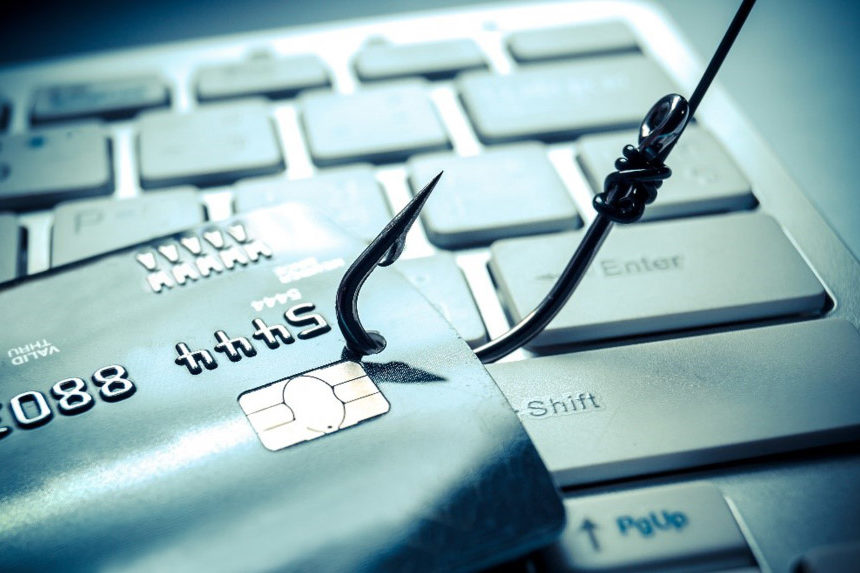 A fish hook pulling a credit card off of a keyboard