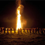 People dancing around a large bonfire