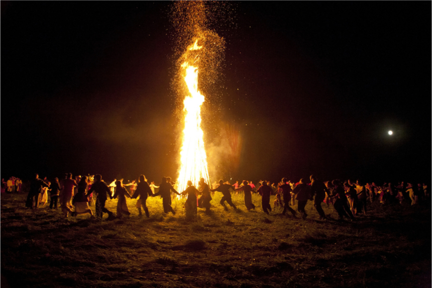 People dancing around a large bonfire