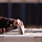 A voting inserts their ballot into a ballot box.
