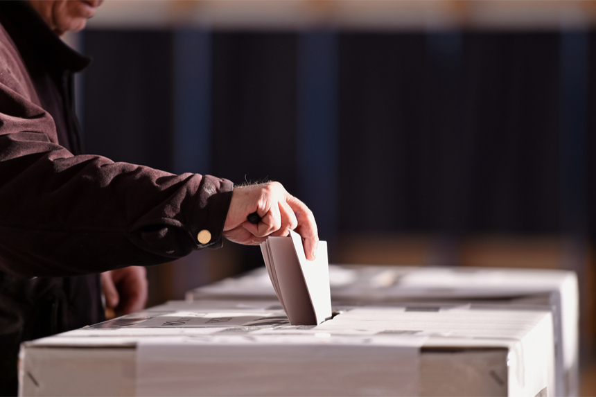 A voting inserts their ballot into a ballot box.
