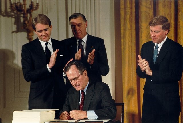 U.S. president George H.W. Bush signing a bill at his desk