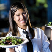 A smiling waiter holding plates of food