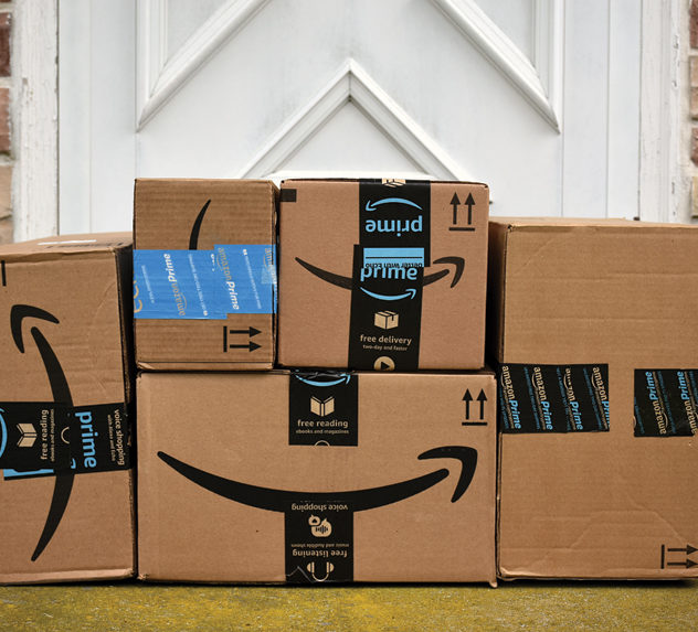 A stack of Amazon packages on a doorstop.