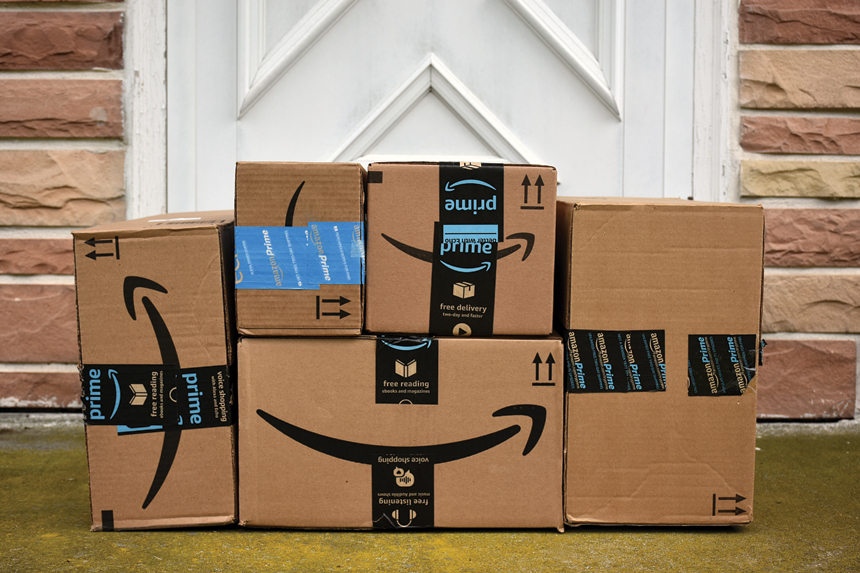 A stack of Amazon packages on a doorstop.