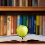 A tart apple resting on an open book in the middle of a library