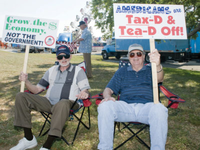 Two protesters during a Tea Party event holding placards while sitting in lawn chairs