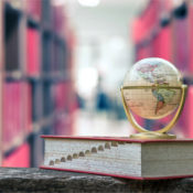 A miniature globe sits on a thesaurus in a library