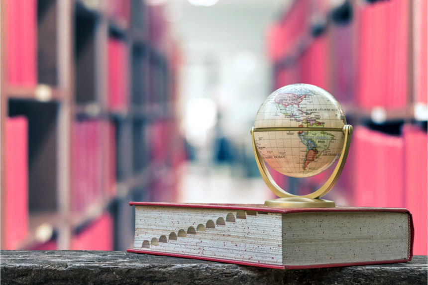 A miniature globe sits on a thesaurus in a library