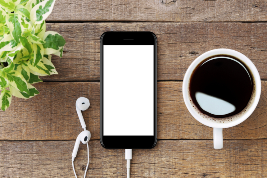 An iPhone and a cup of coffee on a wooden table