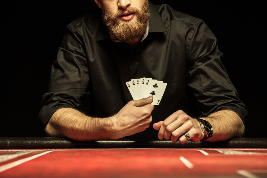 A bearded man showing his cards at a poker table. Gambling like this in your own home is illegal in many state governments.