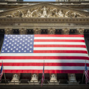 The front facade of the New York Stock Exchange, with the U.S. flag tied to the front columns.