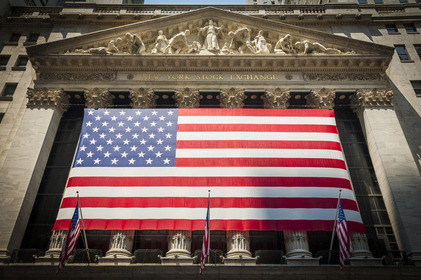 The front facade of the New York Stock Exchange, with the U.S. flag tied to the front columns.