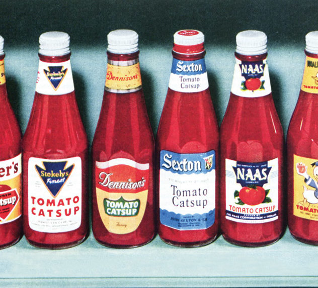Ketchup bottles neatly aligned in a row on a shelf.