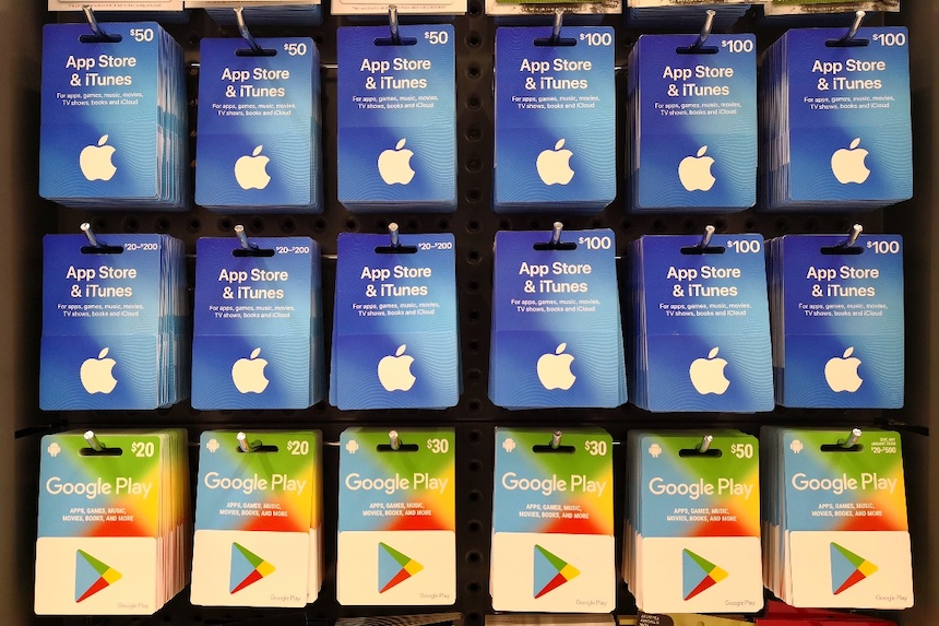 A collection of Apple and Google gift cards hanging on a store's rack.