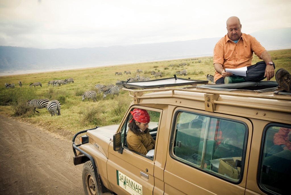 Celebrity chef Andrew Zimmern sits on top of a SUV during a trip to Africa