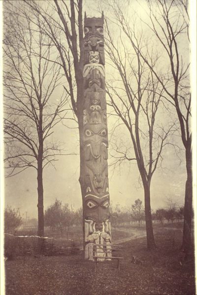 A totem pole sits among trees on a hill