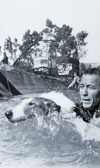 Lassie swimming in a river with fellow actor Robert Bray