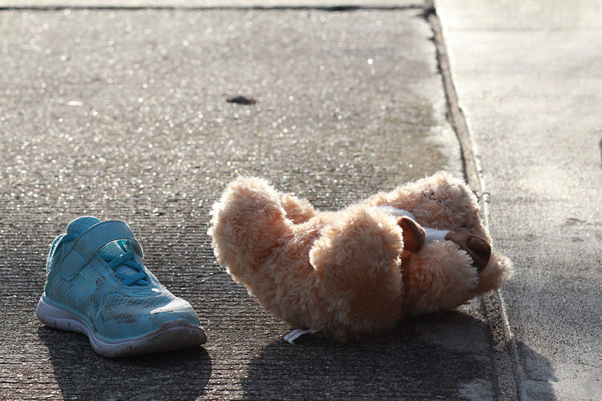 Teddy bear and a child's shoe in the middle of a street