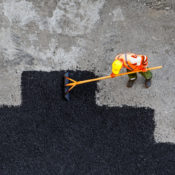 Construction worker laying down asphalt over an old road