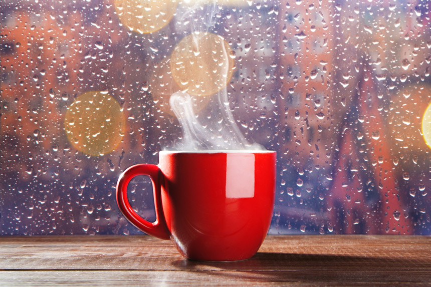 Hot tea in front of a wet window.
