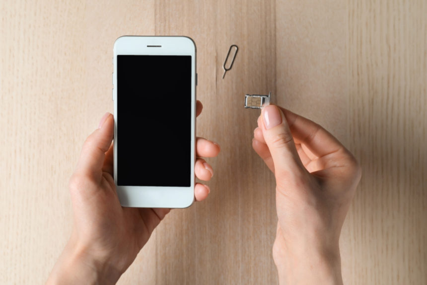 A woman inserting a SIM card into her iPhone.