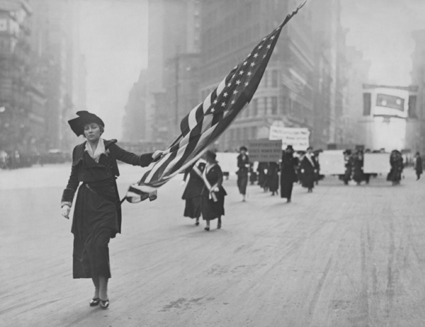 Neysa McMein, waving a U.S. flag, in a women's rights march in New York City.