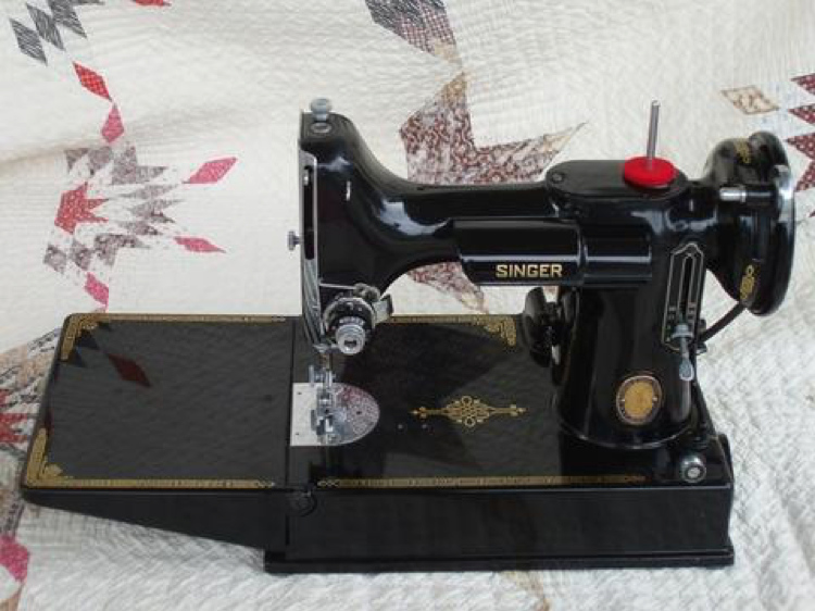 An antique Singer sewing machine from the early 1950s rests on table cloth.