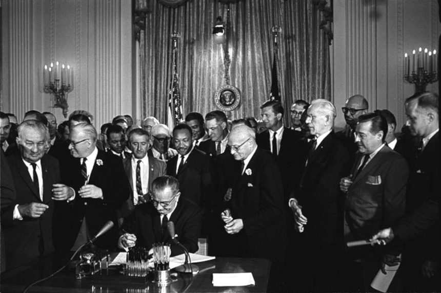 Lyndon B. Johnson signing the Civil Rights Act of 1964, while Dr. Martin Luther King, Jr. looks on