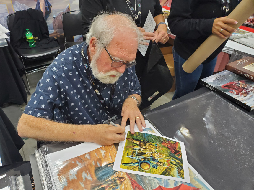 Fantasy artist Larry Elmore signing autographs on copies of his illustrations.