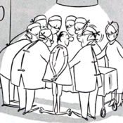 A patient stands with a group of doctors around an operating table.