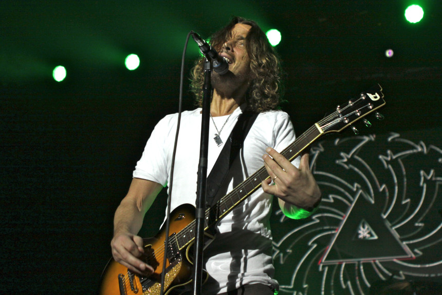 Chris Cornell on stage, signing and playing a guitar.