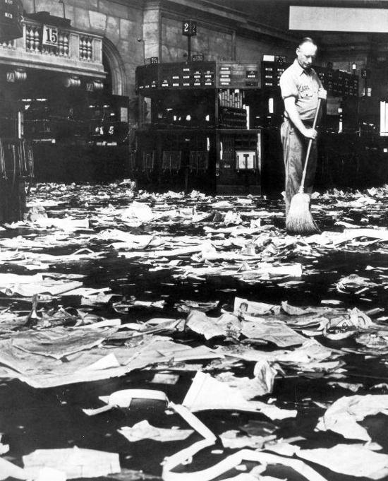 A cleaner sweeping away discarded paper on the floor of the New York Stock Exchange.