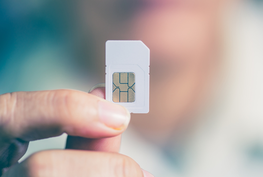 A close-up of a SIM card being held between two fingers.