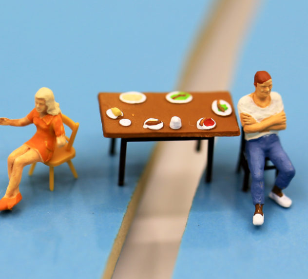 Miniature figures of a couple having an argument at a dinner table.