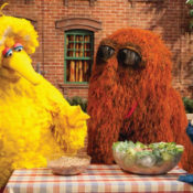 Big Bird and his friends, Snuffleupagus and the Cookie Monster, at a picnic table discussing the health benefits of vegetables.